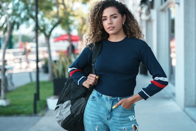 Jovem mulher latina com cabelos cacheados, sorrindo enquanto caminhava ao ar livre na rua. conceito urbano.