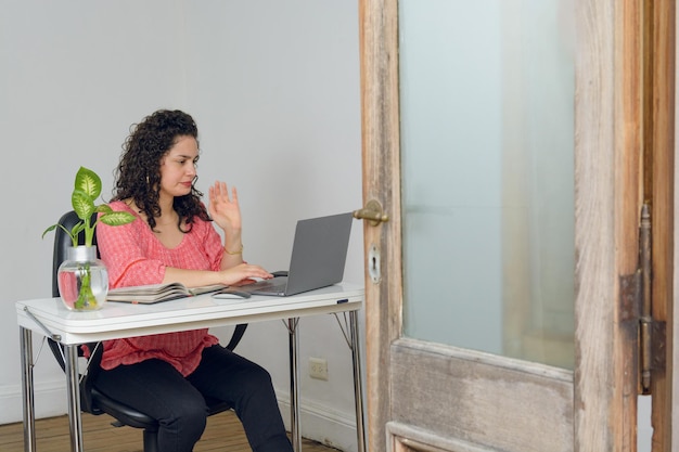 jovem mulher latina com seu laptop sentada trabalhando em seu negócio on-line em casa