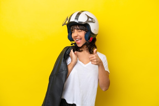 Jovem mulher latina com um capacete de moto isolado em fundo amarelo