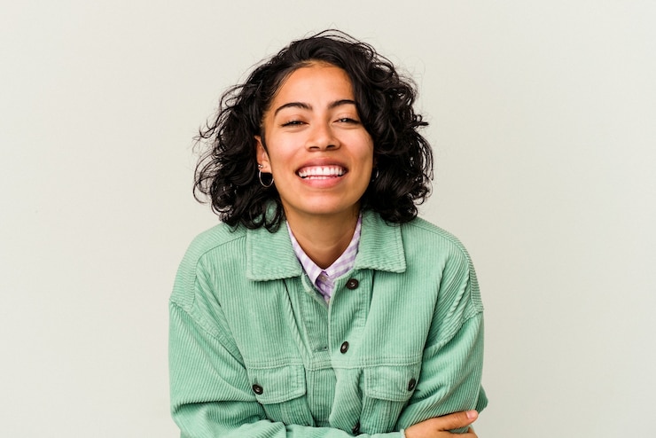 Foto jovem mulher latina encaracolada isolada no fundo branco, rindo e se divertindo.