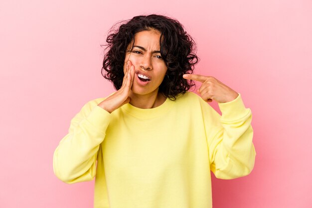 Jovem mulher latina encaracolada isolada no fundo rosa, tendo uma forte dor nos dentes, dor molar.