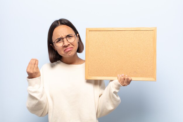 Jovem mulher latina fazendo capice ou gesto de dinheiro, mandando você pagar suas dívidas!