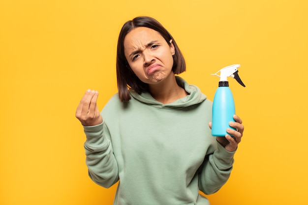 Jovem mulher latina fazendo capice ou gesto de dinheiro, mandando você pagar suas dívidas!