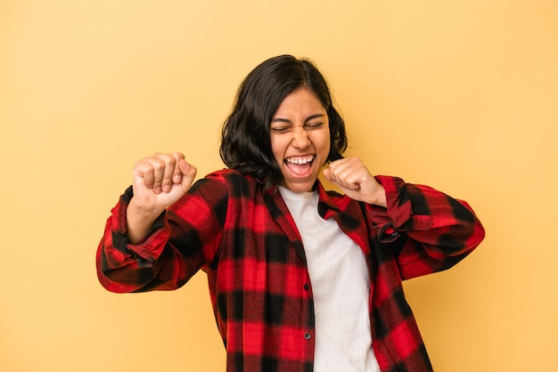 Jovem mulher latina isolada em fundo amarelo, dançando e se divertindo.