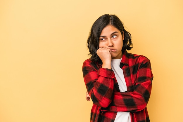 Jovem mulher latina isolada em um fundo amarelo que se sente triste e pensativa, olhando para o espaço da cópia.