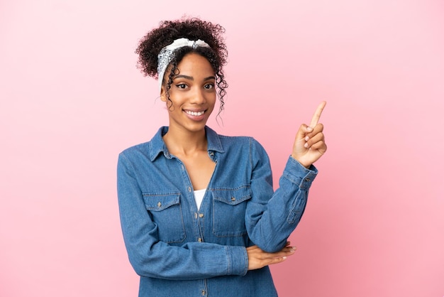 Jovem mulher latina isolada em um fundo rosa feliz e apontando para cima