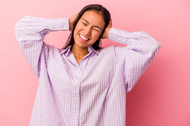 Jovem mulher latina isolada em um fundo rosa gritando, muito animada, apaixonada, satisfeita com alguma coisa.