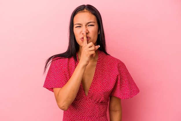 Jovem mulher latina isolada em um fundo rosa, mantendo um segredo ou pedindo silêncio.