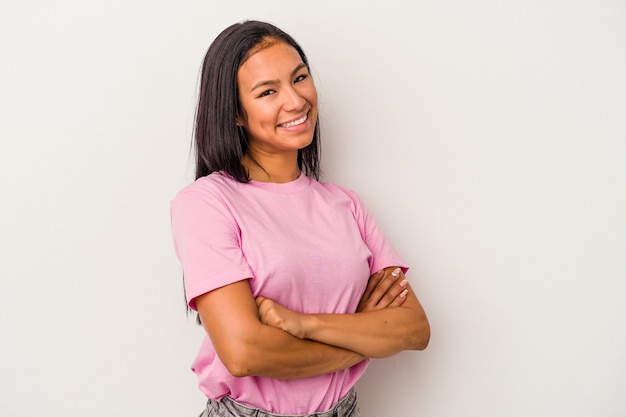 Jovem mulher latina isolada no fundo branco que se sente confiante, cruzando os braços com determinação.