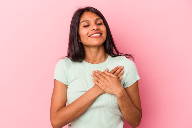 Jovem mulher latina isolada no fundo rosa rindo mantendo as mãos no coração, o conceito de felicidade.