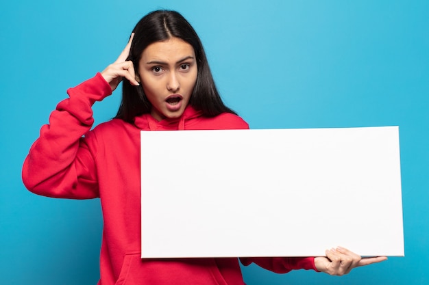 Jovem mulher latina parecendo surpresa, boquiaberta, chocada, percebendo um novo pensamento, ideia ou conceito