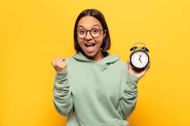 Jovem mulher latina se sentindo chocada, animada e feliz, rindo e comemorando o sucesso, dizendo uau!