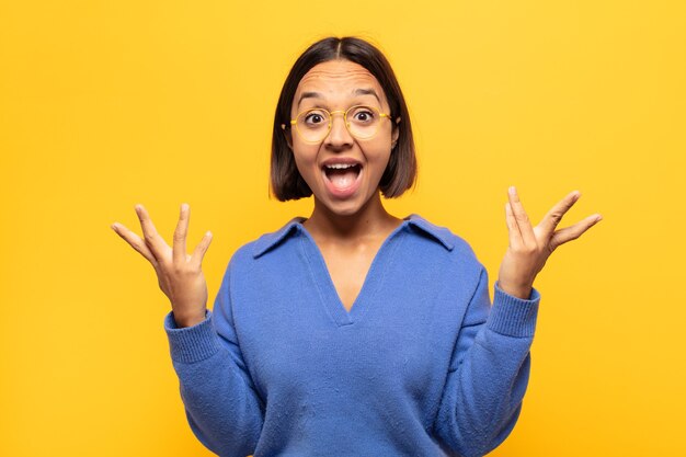 Jovem mulher latina se sentindo feliz, animada, surpresa ou chocada, sorrindo e atônita com algo inacreditável