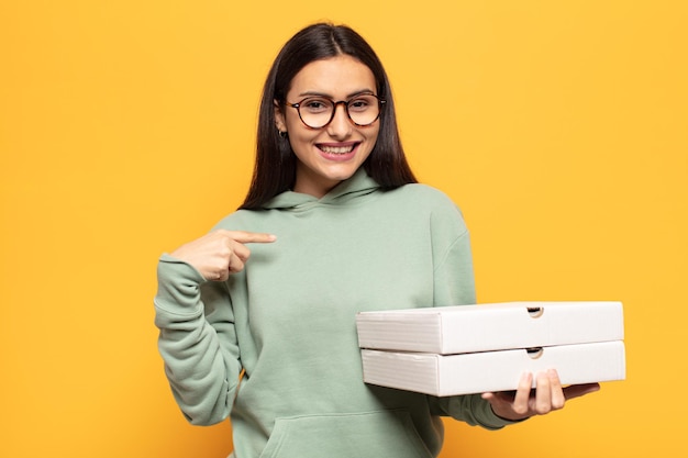 Jovem mulher latina se sentindo feliz, surpresa e orgulhosa, apontando para si mesma com um olhar animado e surpreso