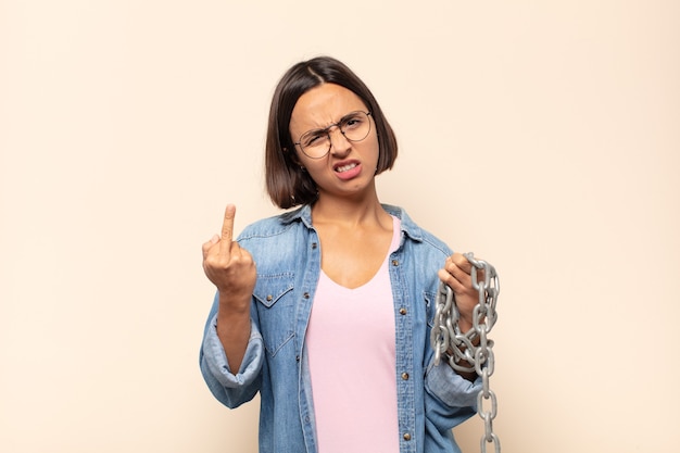 Jovem mulher latina se sentindo irritada, irritada, rebelde e agressiva, sacudindo o dedo do meio e revidando