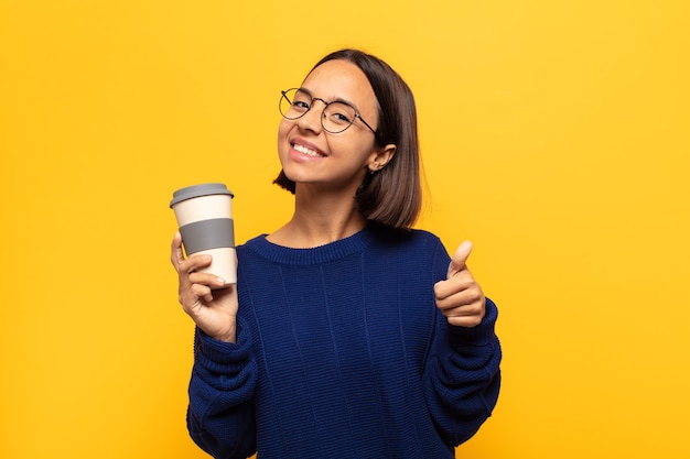 Jovem mulher latina se sentindo orgulhosa, despreocupada, confiante e feliz, sorrindo positivamente com o polegar para cima