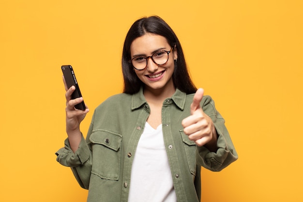 Jovem mulher latina se sentindo orgulhosa, despreocupada, confiante e feliz, sorrindo positivamente com o polegar para cima