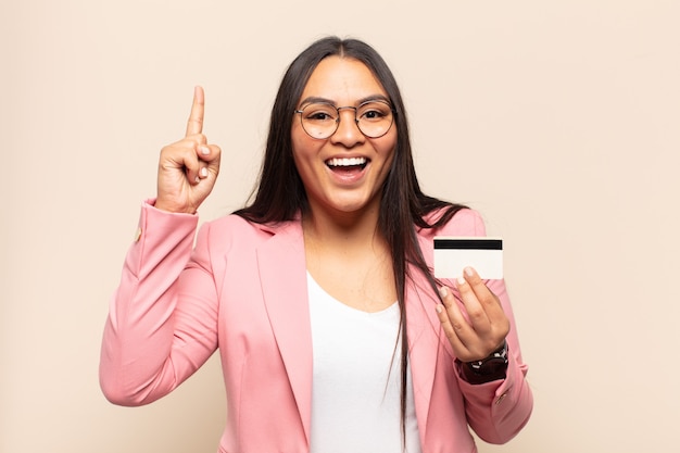 Jovem mulher latina se sentindo um gênio feliz e animado depois de realizar uma ideia, levantando o dedo alegremente, eureka!