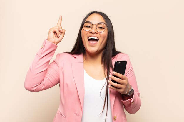 Jovem mulher latina se sentindo um gênio feliz e animado depois de realizar uma ideia, levantando o dedo alegremente, eureka!