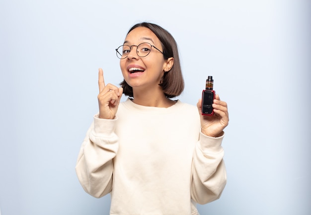 Jovem mulher latina se sentindo um gênio feliz e animado depois de realizar uma ideia, levantando o dedo alegremente, eureka!