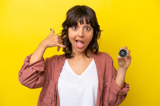 Foto jovem mulher latina segurando bússola isolada em fundo amarelo fazendo gesto de telefone ligue-me de volta sinal