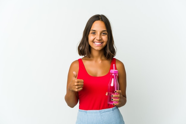 Jovem mulher latina segurando um milkshake isolado no fundo branco, sorrindo e levantando o polegar