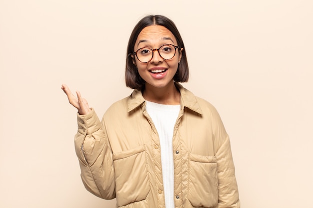 Jovem mulher latina sentindo-se feliz, surpresa e alegre, sorrindo com atitude positiva, percebendo uma solução ou ideia