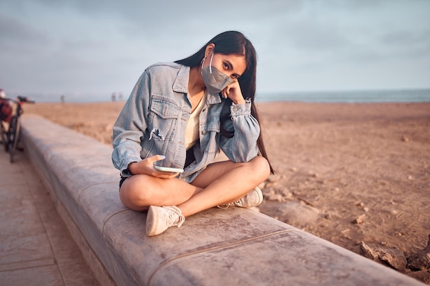 Foto jovem mulher latina sorri durante um belo pôr do sol mulher jovem feliz com máscara