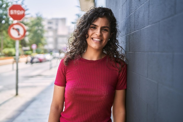 Jovem mulher latina sorrindo confiante em pé na rua