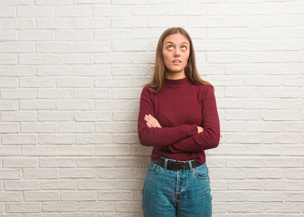 Jovem mulher legal sobre uma parede de tijolos cansado e entediado