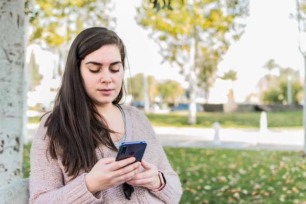 Jovem mulher lendo mensagem no parque