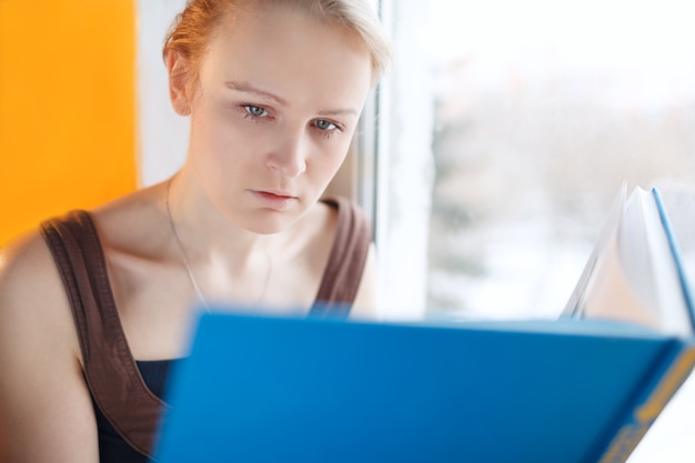 Jovem mulher lendo um livro com capa azul