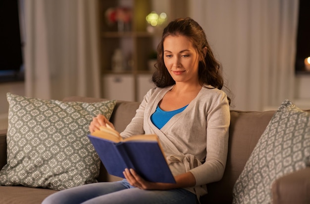 jovem mulher lendo um livro em casa à noite