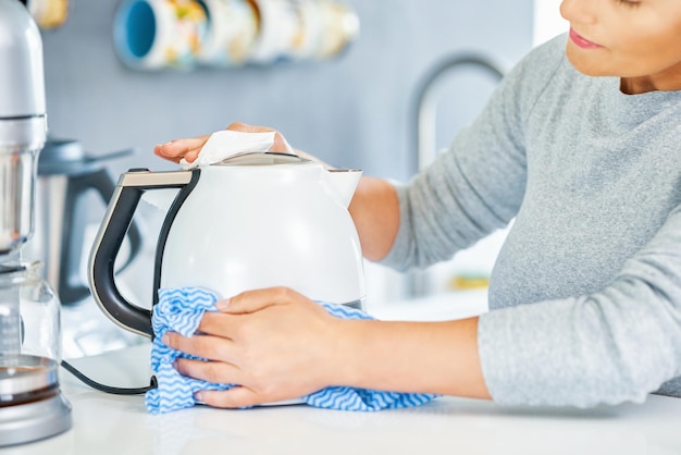 Jovem mulher limpando chaleira na cozinha