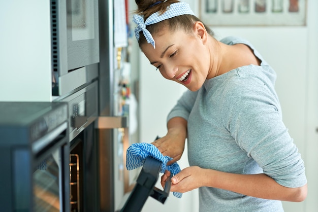 Jovem mulher limpando o forno na cozinha