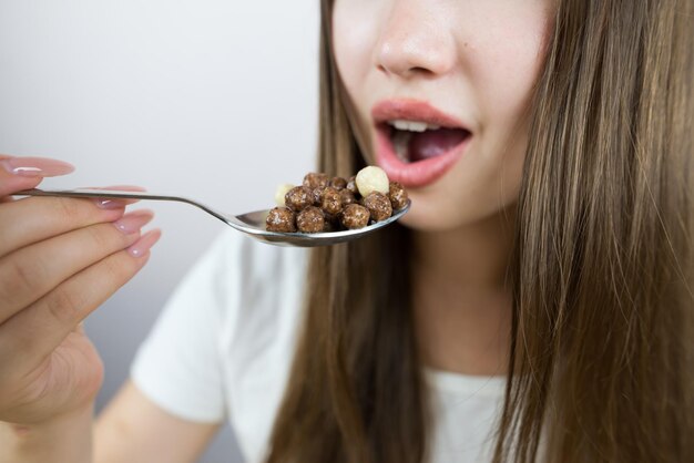 Jovem mulher linda comendo bolas de pequeno-almoço seco com leite