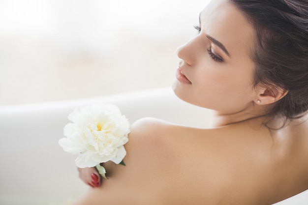 Foto jovem mulher linda tomando banho com flores e leite