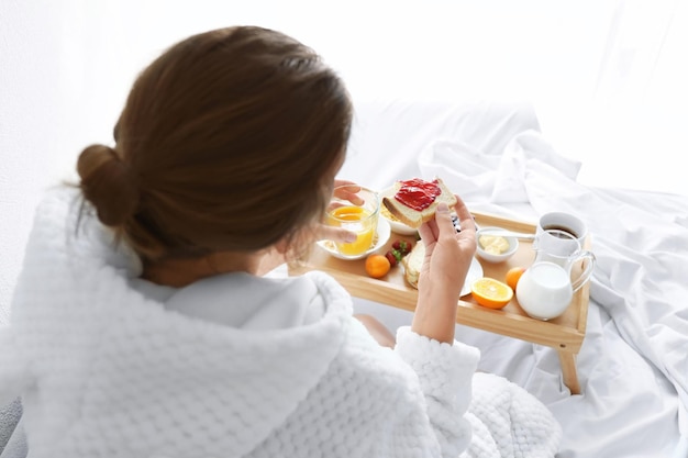 Jovem mulher linda tomando café da manhã na cama
