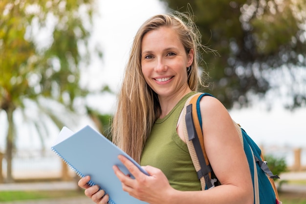 Jovem mulher loira ao ar livre segurando um caderno