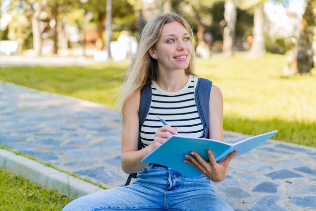 Jovem mulher loira ao ar livre segurando um notebook