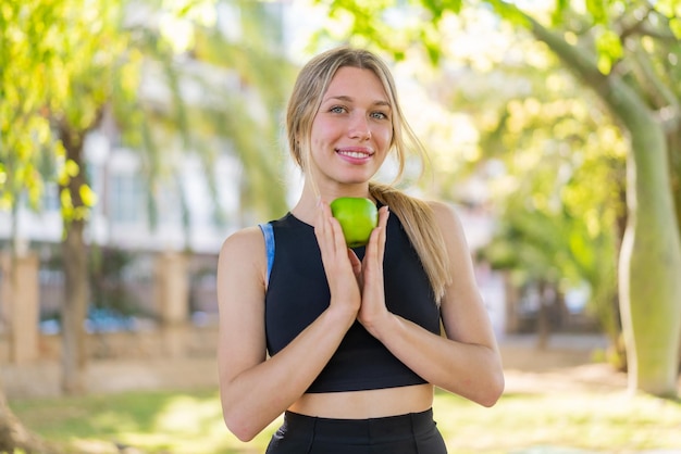 Foto jovem mulher loira ao ar livre segurando uma maçã