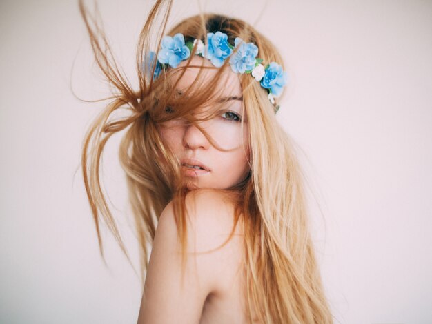 Jovem mulher loira, ao vento, com uma coroa de flores