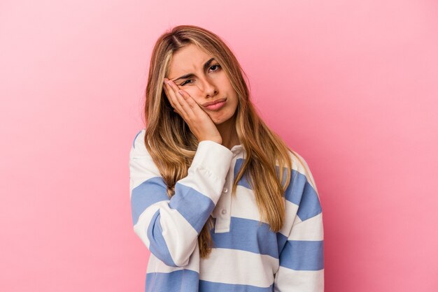 Jovem mulher loira caucasiana, cansada e com muito sono, mantendo a mão na cabeça.