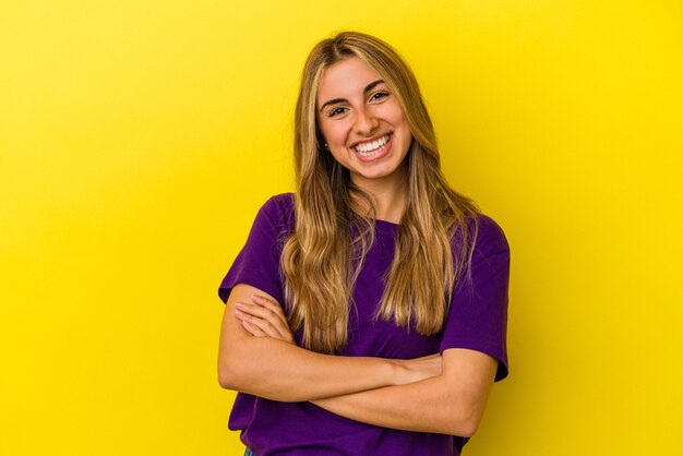 Jovem mulher loira caucasiana isolada em fundo amarelo feliz, sorridente e alegre.