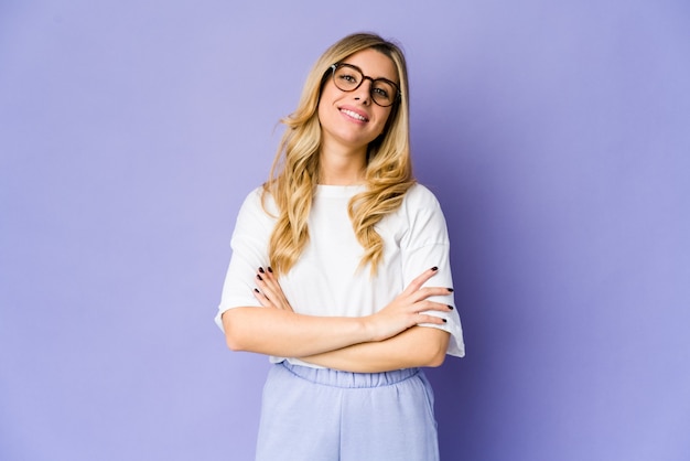 Jovem mulher loira caucasiana que se sente confiante, cruzando os braços com determinação.