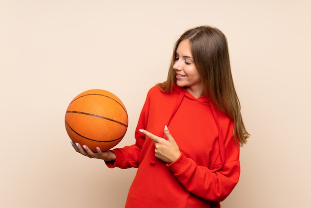 Jovem mulher loira com bola de basquete e apontando-o