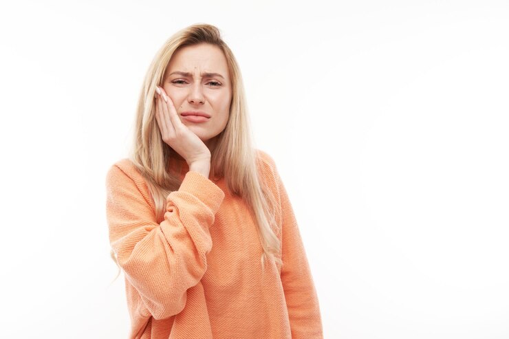 Foto jovem mulher loira com expressão de rosto sofredor segura bochecha com mão tocando a boca com a palma da mão isolada no fundo branco conceito de dor de dente