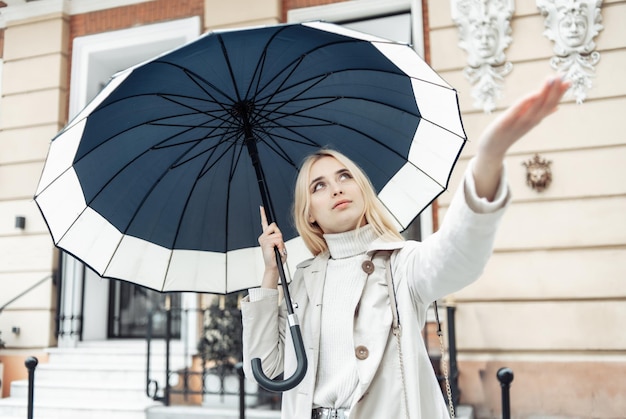 Jovem mulher loira com guarda-chuva esperando a chuva na cidade