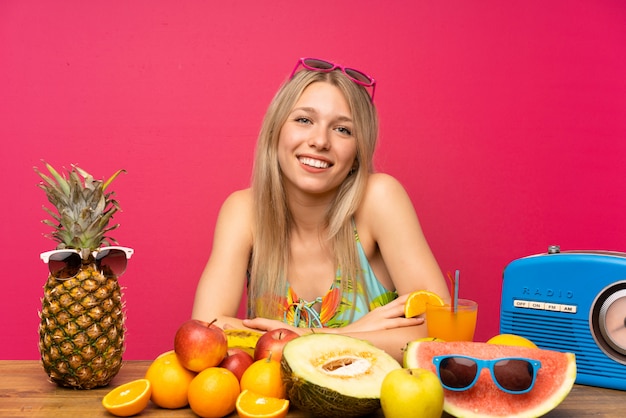 Jovem mulher loira com muitas frutas rindo