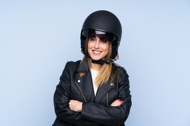 Jovem mulher loira com um capacete de moto sobre parede azul isolada